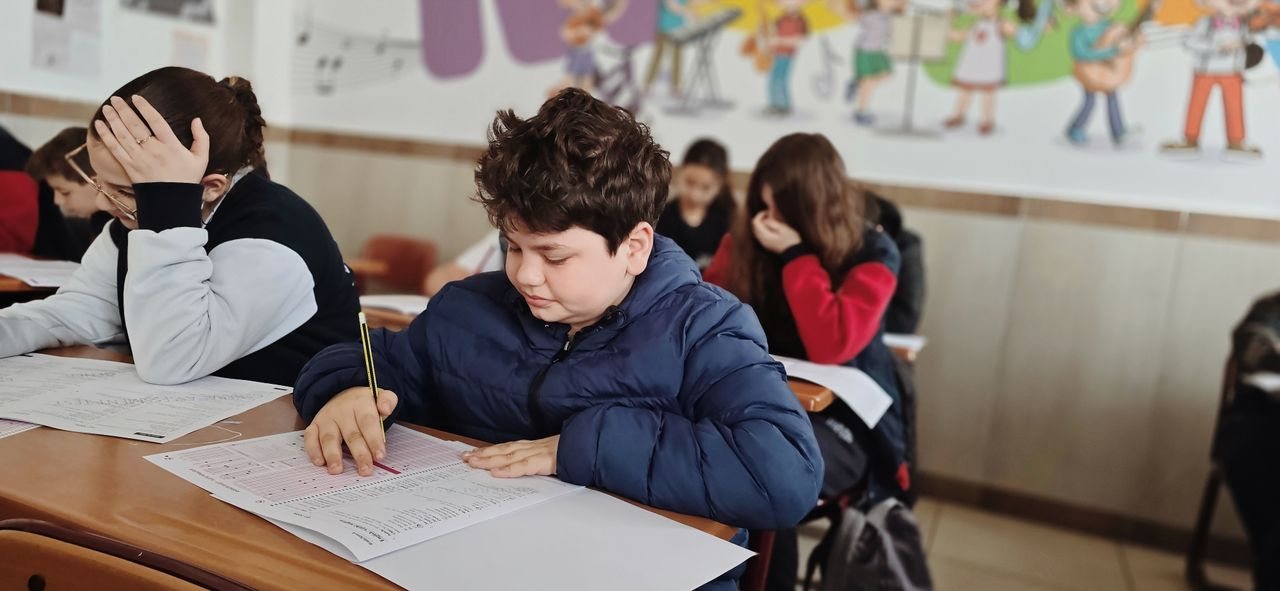 Free A group of children taking a test with focus and concentration in a classroom setting. Stock Photo