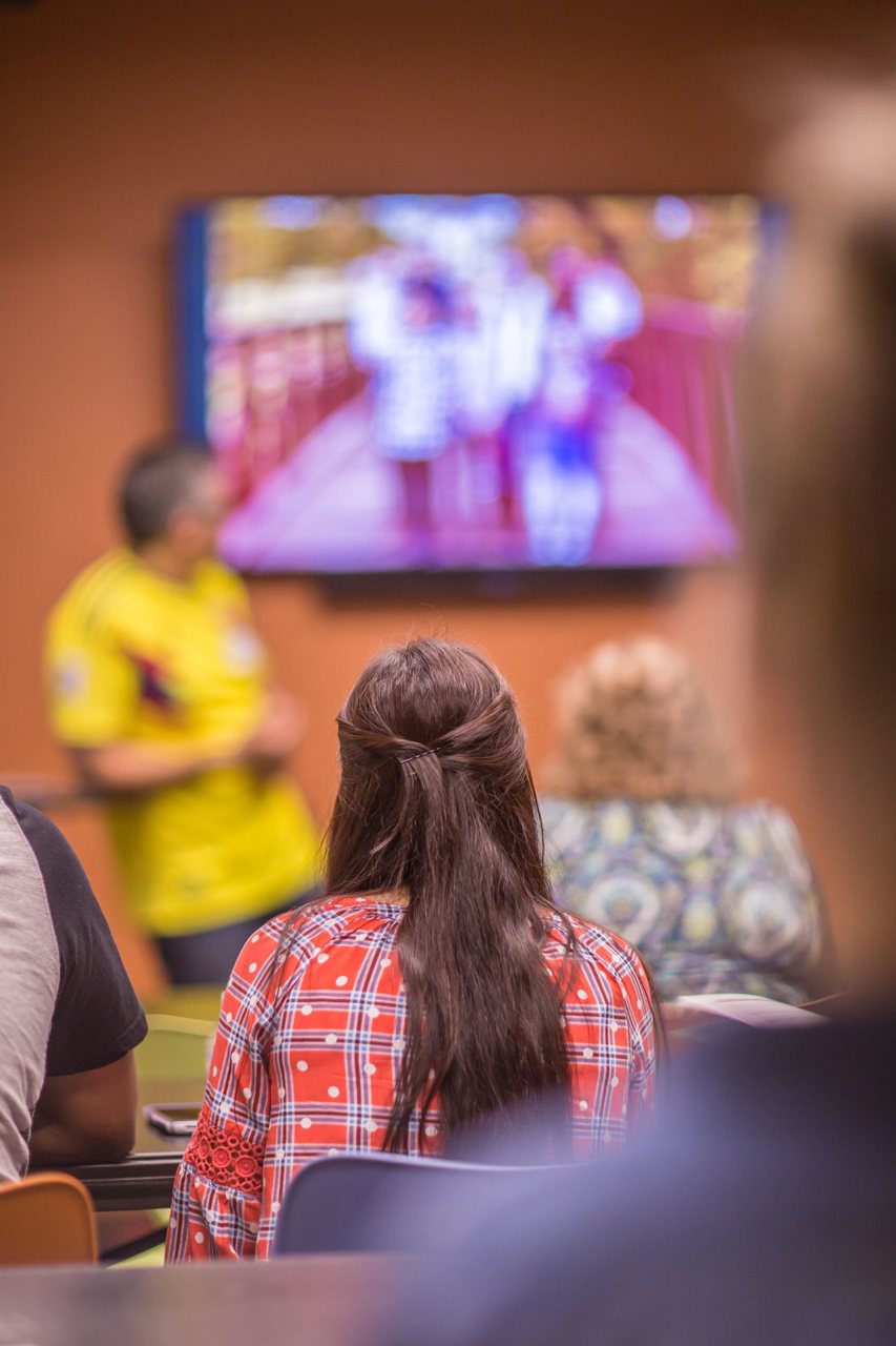 Free Students listening to a classroom presentation with a blurred image on the projector screen. Stock Photo