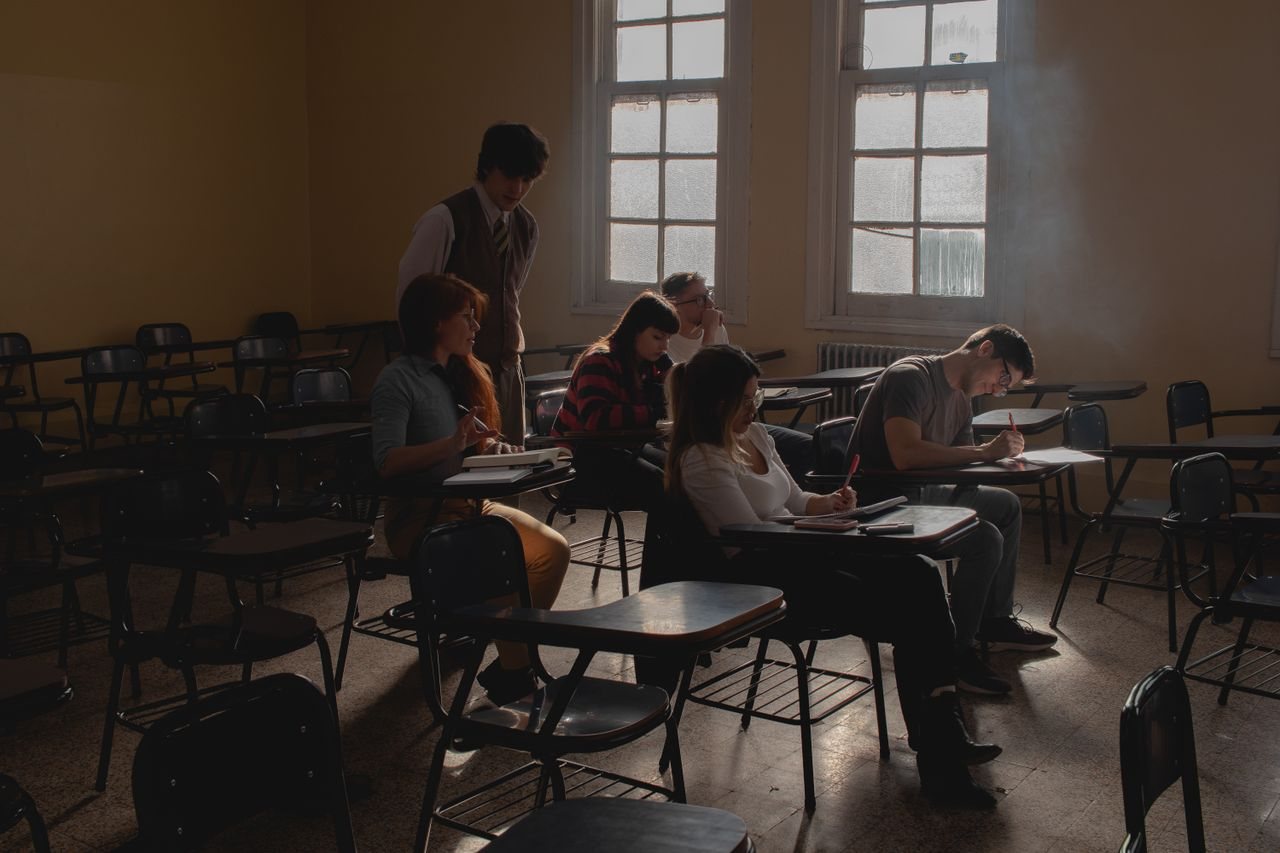 Free Group of students studying in a dimly lit classroom with vintage desks and natural light. Stock Photo